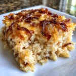 A close-up of a square serving of creamy french onion butter rice topped with crispy, caramelized onions.