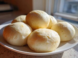 A plate holding several smooth, light yellow balls of freshly made fufu, ready to eat.