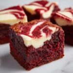 Close-up of a fudgy red velvet brownie square topped with a cream cheese swirl.
