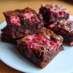 Close-up of fudgy strawberry brownies featuring a bright pink strawberry swirl and chocolate chips.