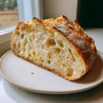 Close-up of a thick slice of homemade garlic parmesan bread showing an open, airy crumb structure.