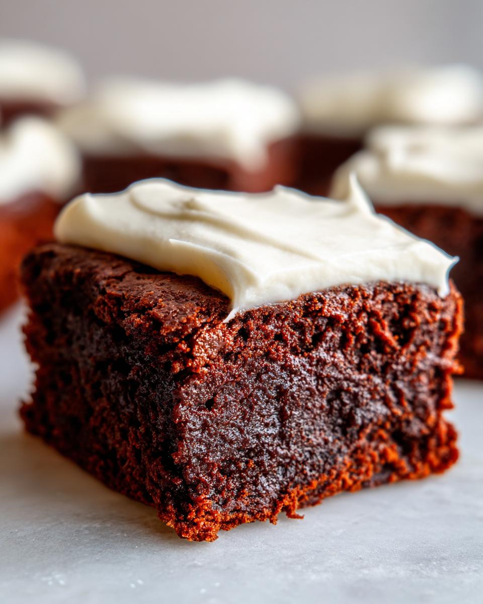 Close-up of a rich, dark brown gingerbread brownies square topped with thick, white cream cheese frosting.