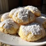 A stack of freshly baked, soft gooey butter cookies generously dusted with white powdered sugar.