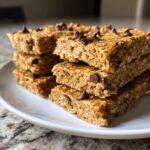 A stack of delicious, homemade chocolate chip protein bars made with oats, sitting on a white plate.