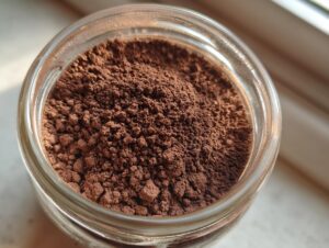 Overhead close-up view of rich brown homemade hot cocoa mix filling a clear glass jar.