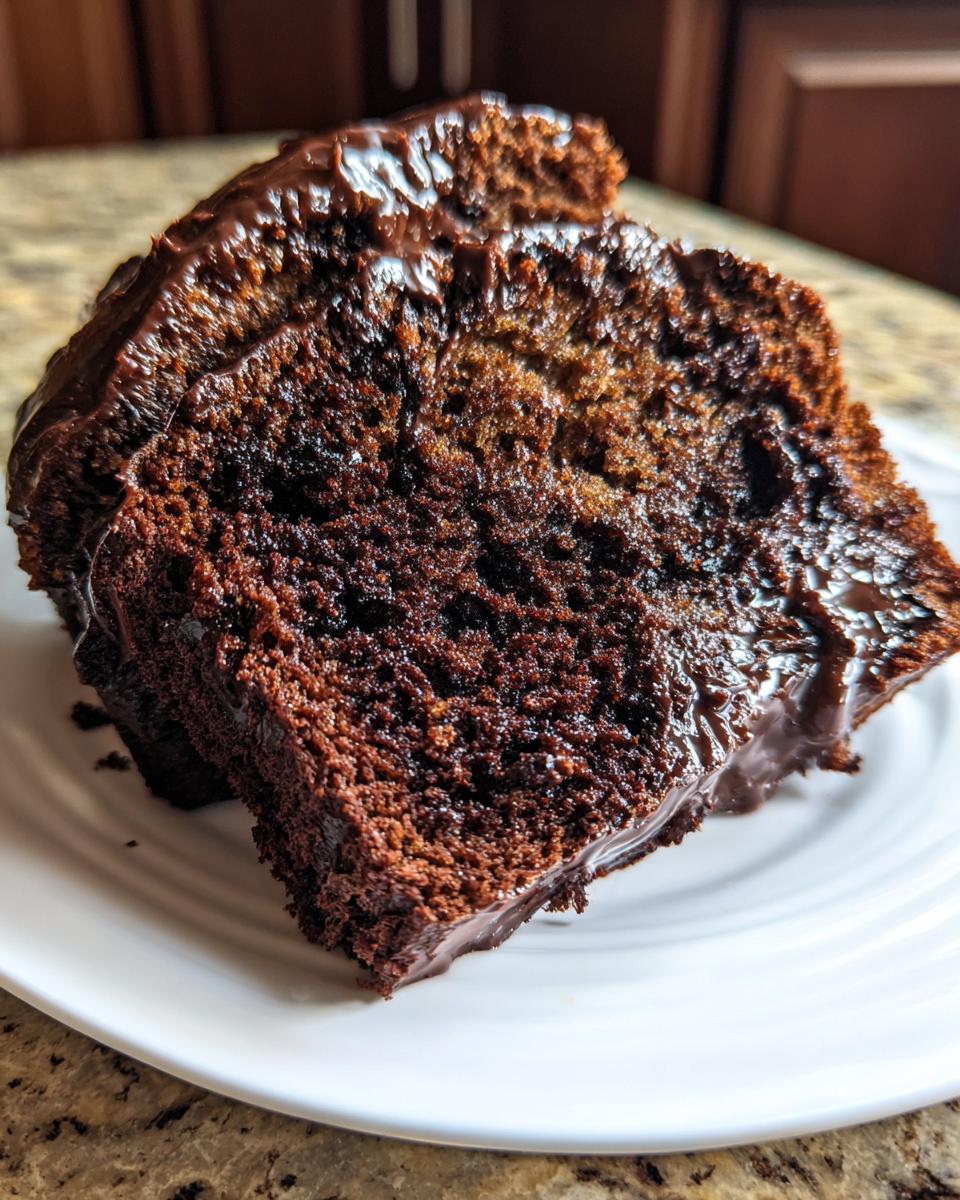 Close-up of a rich, dark slice of hot fudge brownie bread topped with glossy chocolate fudge icing.