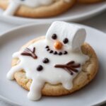 A single, delicious melted snowman cookie featuring a marshmallow head, white icing body, and chocolate chip details, ready to eat.