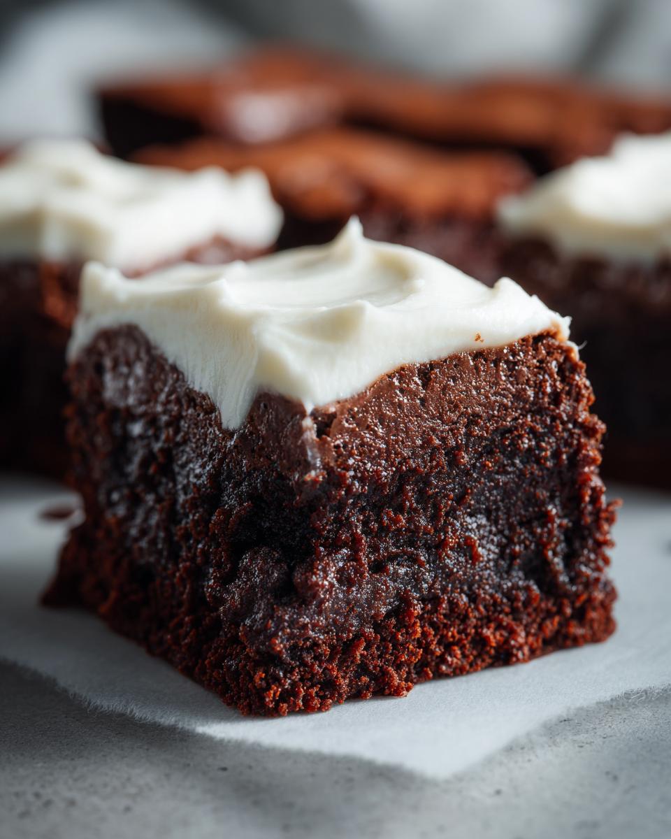 Close-up of a rich, dark gingerbread brownies square topped with thick white cream cheese frosting.