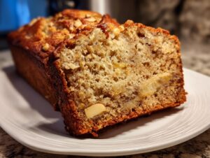 Close-up of a moist slice of Hawaiian banana bread showing soft crumb, banana pieces, and chopped nuts.
