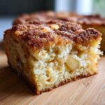 Close-up of a moist slice of jewish apple cake showing tender crumb and chunks of baked apple.