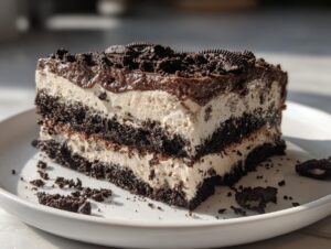 A thick slice of no-bake Oreo dirt cake showing alternating layers of chocolate cookie crumbs and creamy filling.