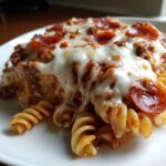 Close-up of a serving of pizza pasta bake featuring rotini pasta, meat sauce, melted mozzarella, and pepperoni slices.