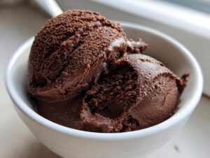 Two scoops of rich, dark homemade chocolate pudding served in a small white bowl.
