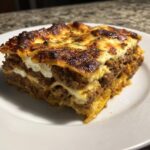 A thick, cheesy slice of sheet pan lasagna with browned top and rich meat sauce layers.