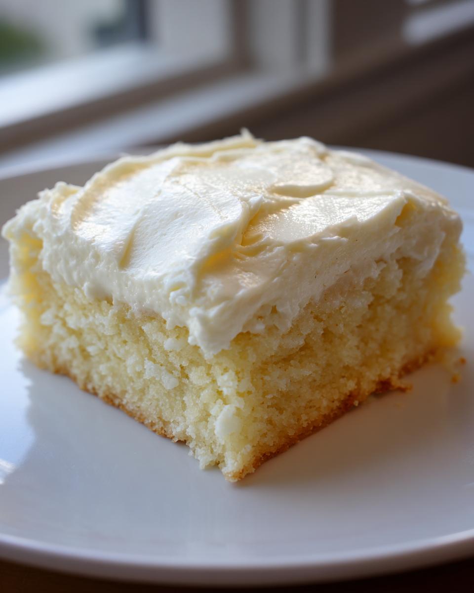 Close-up of a square slice of soft sugar cookie bars topped with thick white frosting.