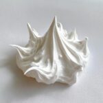 A dollop of thick, glossy white royal icing showing stiff peaks, perfect for gingerbread house icing.