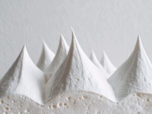 Close-up of stiff, white royal icing piped into sharp peaks, demonstrating strong gingerbread house icing texture.