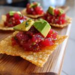 Close-up of fresh tuna tartare topped with avocado cubes served on a crispy wonton chip.