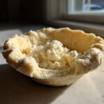 Close-up of an unbaked butter pie crust shell filled with cold, crumbly chunks of butter or fat.