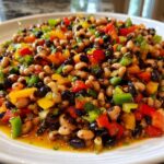 Close-up of a colorful cowboy caviar dip featuring black-eyed peas, black beans, and diced red, yellow, and green bell peppers.
