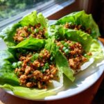 Close-up of three servings of amazing chicken lettuce wraps filled with savory ground chicken and topped with green onions.