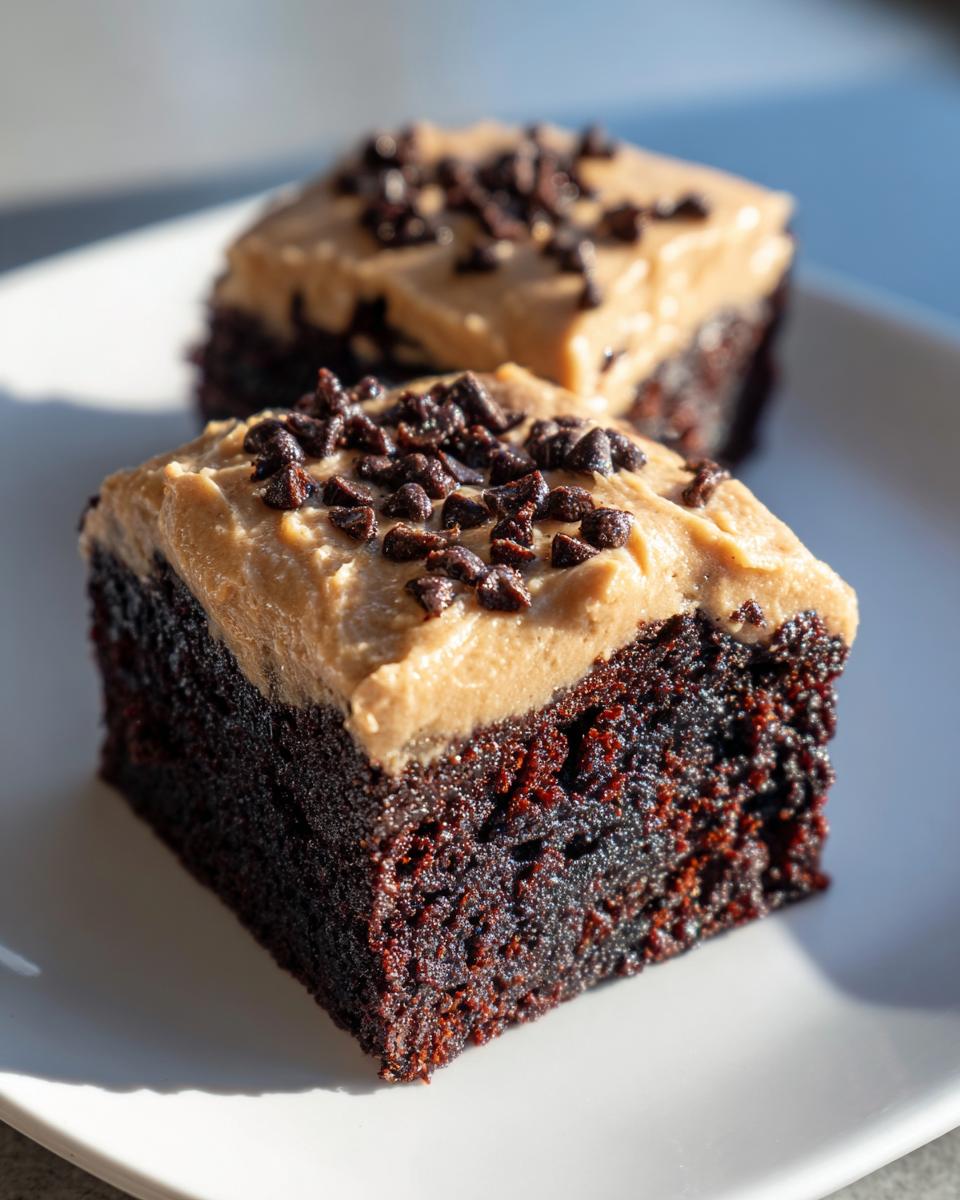 Two rich, dark chocolate banana bread brownies topped with creamy peanut butter frosting and mini chocolate chips.