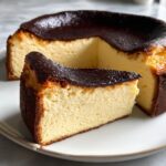 A close-up of a creamy slice of Basque burnt cheesecake with its signature dark, caramelized top.