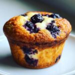 A close-up of a perfectly baked blueberry cream cheese muffins with a golden-brown top.