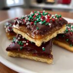 Close-up of stacked Caramel Ritz Cracker Christmas Cookies topped with chocolate and festive red, green, and white sprinkles.