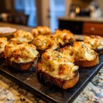 Close-up of cheesy, baked Hanky Panky recipe topping served on toasted baguette slices.