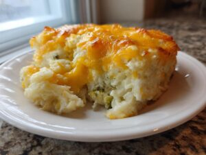 A generous serving of creamy chicken cauliflower rice casserole topped with melted, golden cheddar cheese.