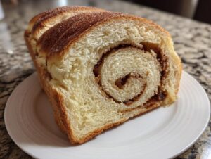 Close-up of a freshly baked loaf slice showing a tight cinnamon swirl filling inside the soft raisin bread.