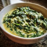 Close-up of a white bowl filled with rich, homemade creamed spinach recipe.