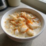 Close-up of a creamy bowl of crab soup topped with orange seasoning and herbs.