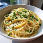 Close-up of creamy pasta coated in sauce, topped with parsley and cheese, representing the garlic parmesan recipe.