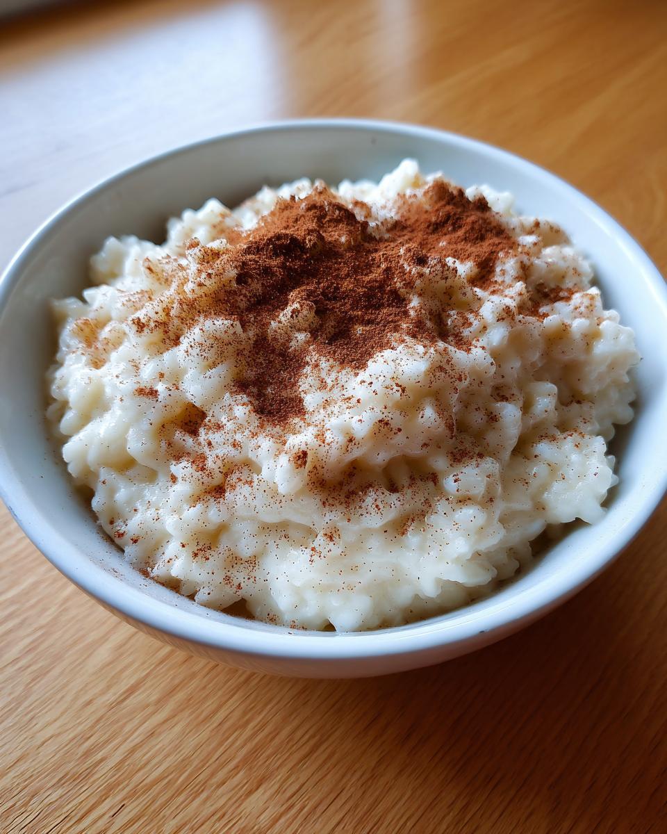 Close-up of a bowl of creamy rice pudding recipe generously dusted with ground cinnamon.