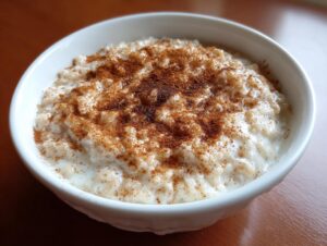 Close-up of a bowl of creamy rice pudding recipe generously sprinkled with ground cinnamon.
