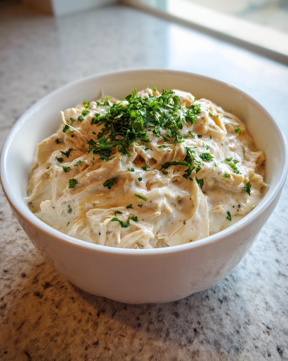 A white bowl filled with creamy white chicken chili topped generously with fresh chopped parsley.