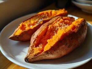 Two halves of a fluffy baked sweet potato, split open and sprinkled with coarse sea salt.