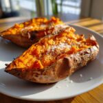 Two halves of a fluffy baked sweet potato topped generously with coarse sea salt.