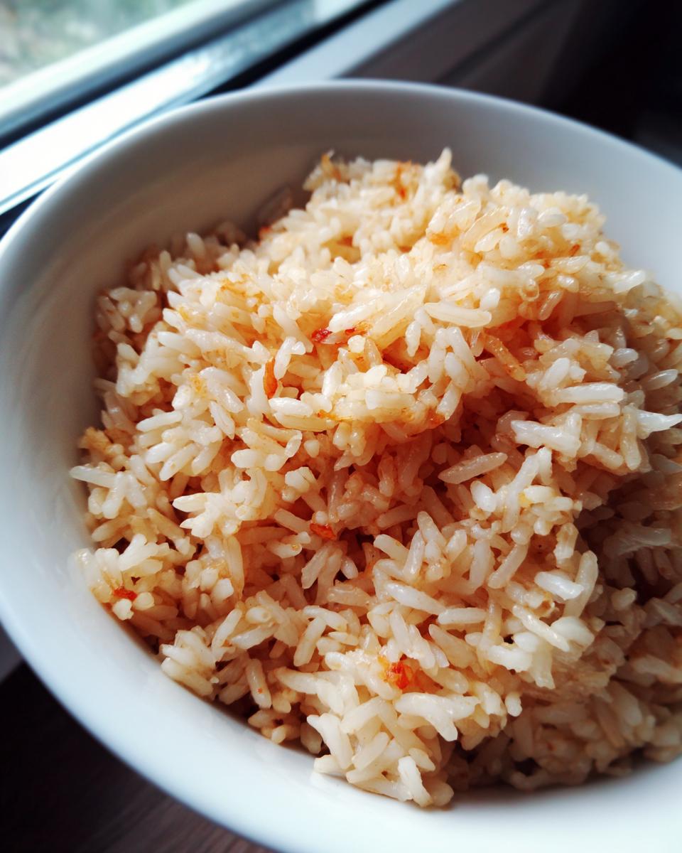 Close-up of fluffy, seasoned white rice in a white bowl, representing perfect spanish rice.