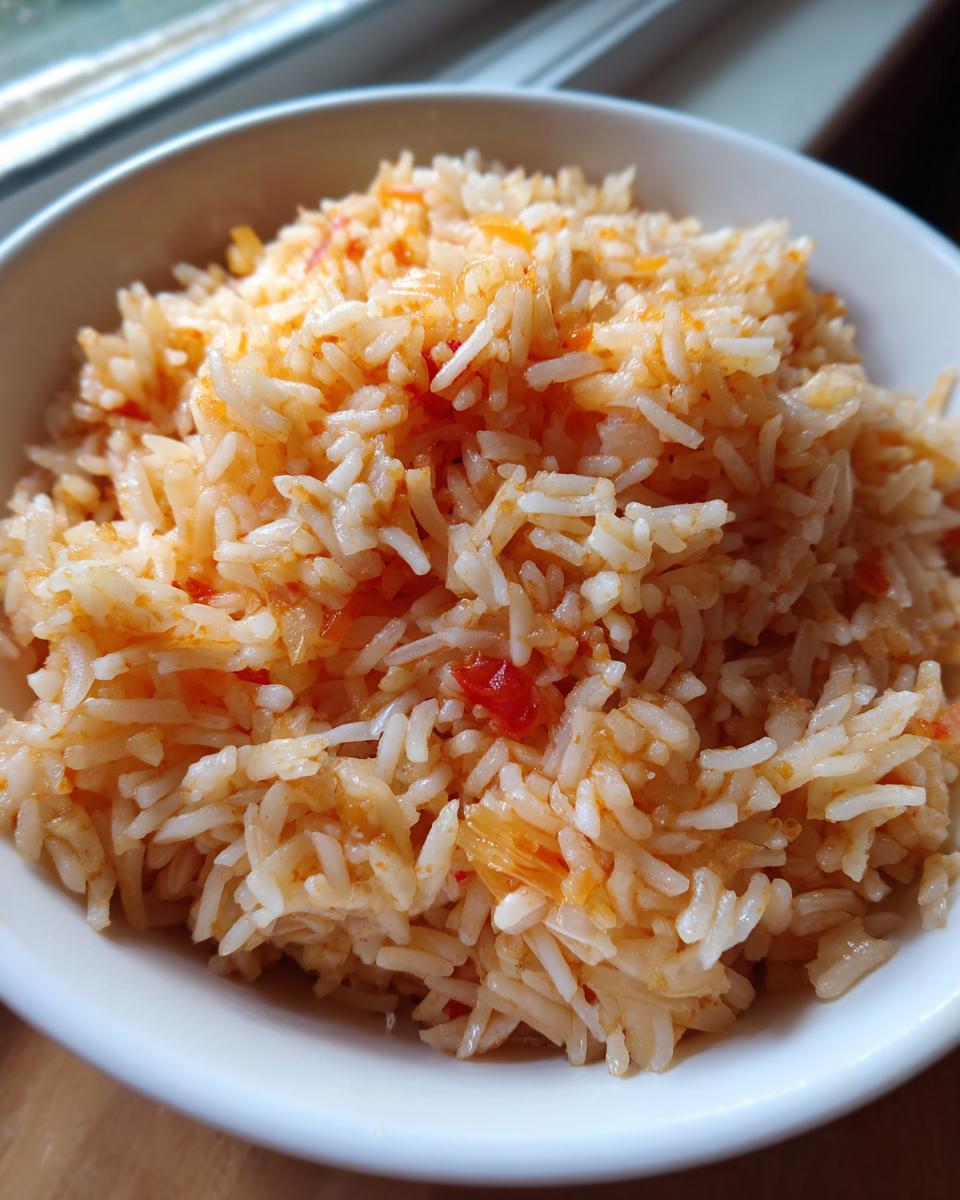 Close-up of fluffy, seasoned white rice with flecks of red tomato, representing perfect Spanish rice.