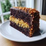 A close-up slice of moist german chocolate cake recipe showing dark chocolate layers and thick coconut-pecan filling.