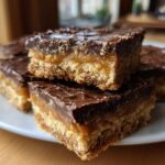 Three stacked squares of rich graham cracker toffee featuring a thick base, gooey caramel layer, and dark chocolate topping.
