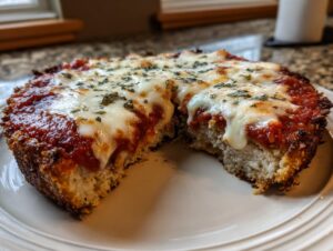 A thick slice of keto chicken parmesan topped with melted mozzarella cheese and marinara sauce, showing the texture of the chicken base.