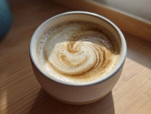 Close-up of a creamy beverage with latte art swirl in a ceramic mug, unrelated to the roasted cauliflower soup.