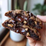 Close-up of a levain bakery chocolate chip cookies half, showing molten chocolate center and walnuts.
