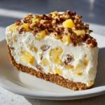 A thick slice of creamy, no-bake Million Dollar Pie featuring pineapple chunks, pecans, and a graham cracker crust.