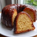 Close-up of a slice of moist Bacardi rum cake, heavily glazed with a dark, shiny rum sauce.