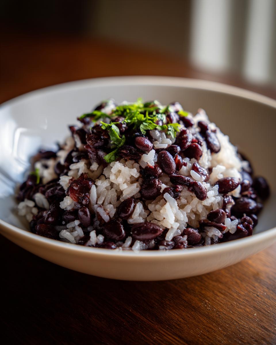 Close-up of a bowl filled with white rice mixed with dark black beans, topped with fresh chopped parsley for our beans and rice recipe.